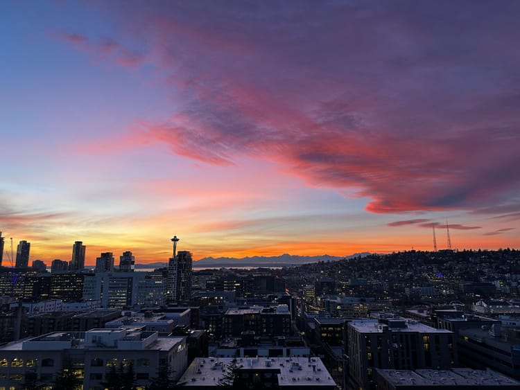 a fiery sunset overlooking Seattle's skyline, Puget Sound, and the Olympic mountains